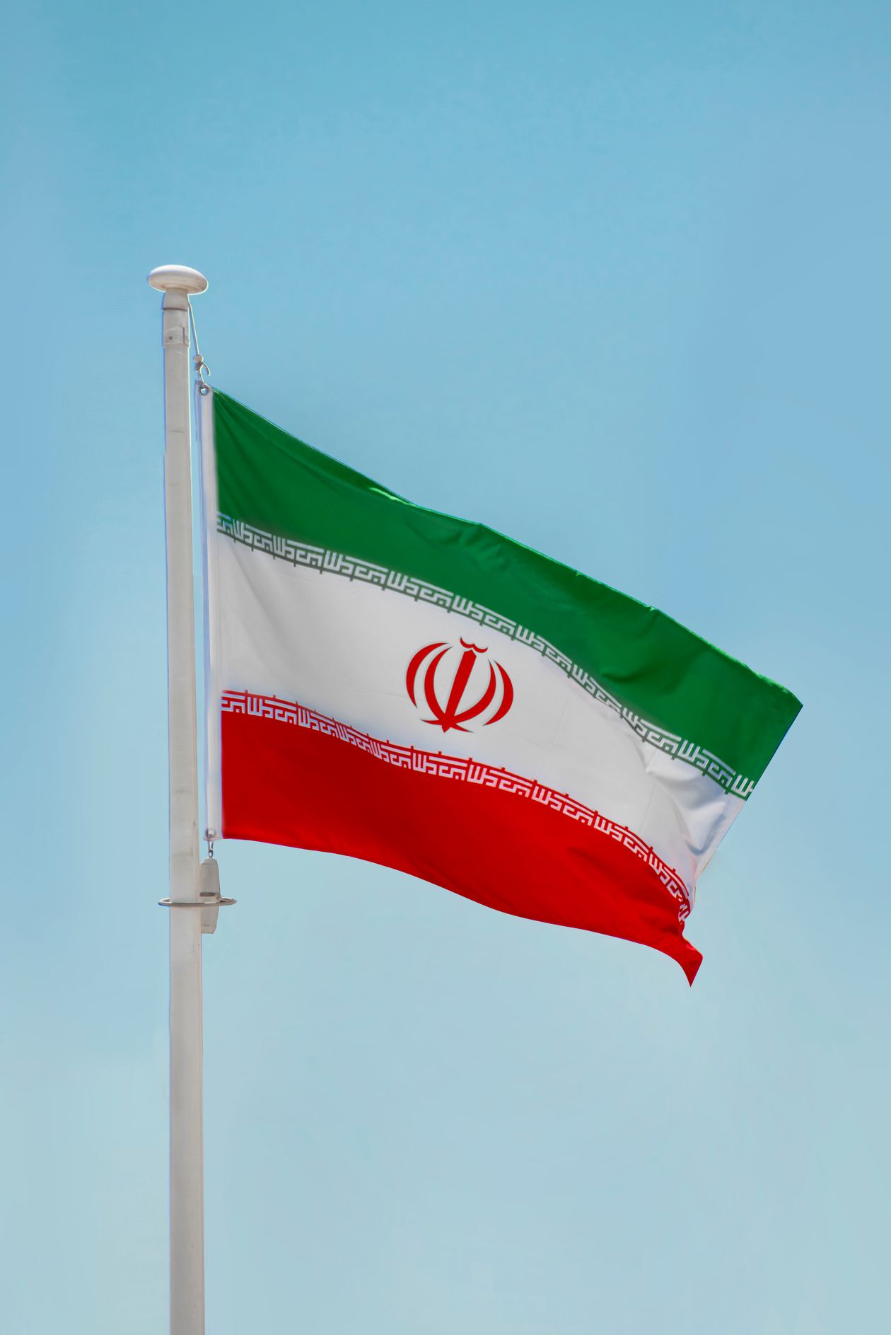 Iranian flag beneath a blue sky in Tehran
